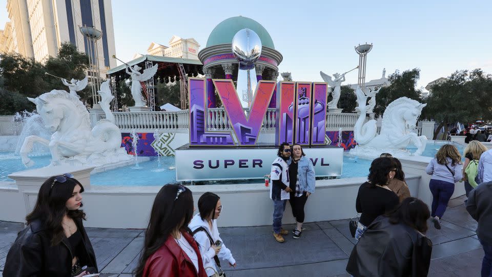 Visitors pose in front of a Super Bowl LVIII logo and an oversized replica of the Vince Lombardi Trophy on the Las Vegas Strip in front of Caesars Palace on February 3, 2024. - Ethan Miller/Getty Images