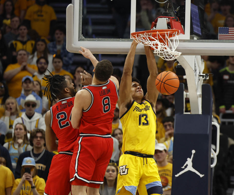 Marquette's Oso Ighodaro (13) dunks against St. John's Ruby Ejiofor, left, and Chris Ludlum during the second half of an NCAA college basketball game Saturday, Feb. 10, 2024, in Milwaukee. (AP Photo/Jeffrey Phelps)