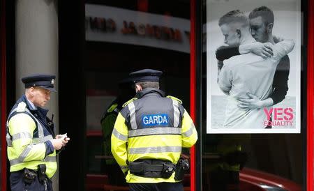 Police officers stop to speak to a man sleeping rough (unseen) next to a poster in favour of same sex marriage in Temple Bar, central Dublin as Ireland holds a referendum on gay marriage, May 22, 2015. REUTERS/Cathal McNaughton