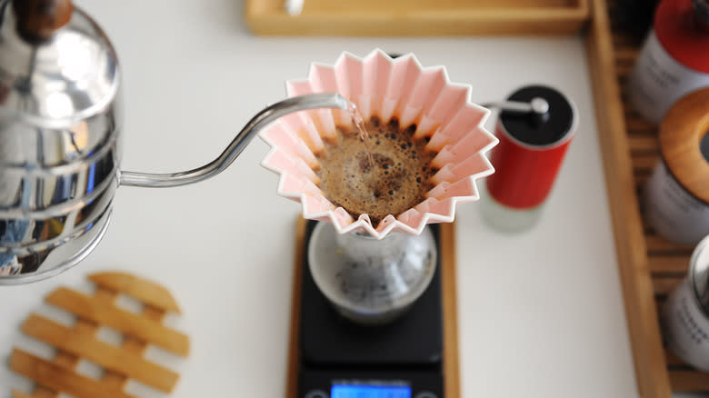 Hands pour oat milk into a cup of coffee