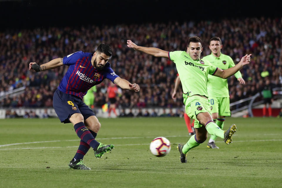 Barcelona forward Luis Suarez, left, attempts a shot at goal in front of Levante's Rober Pier during a Spanish La Liga soccer match between FC Barcelona and Levante at the Camp Nou stadium in Barcelona, Spain, Saturday, April 27, 2019. (AP Photo/Manu Fernandez)