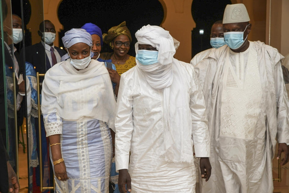 In this photo provided by the Mali Presidency, three-time Malian presidential candidate and ex-hostage Soumaila Cisse, center, is accompanied by his wife Astan Traore, left, and Issoufi Maiga, right, head of the crisis unit for the release of Cisse, as they arrive at the presidential palace after Cisse was released and flown to the capital Bamako, Mali, late Thursday, Oct. 8, 2020. A prominent Malian politician and three European hostages freed by Islamic extremists in northern Mali this week landed in the country's capital late Thursday where they held emotional reunions with family members and were greeted by government officials. (Mali Presidency via AP)