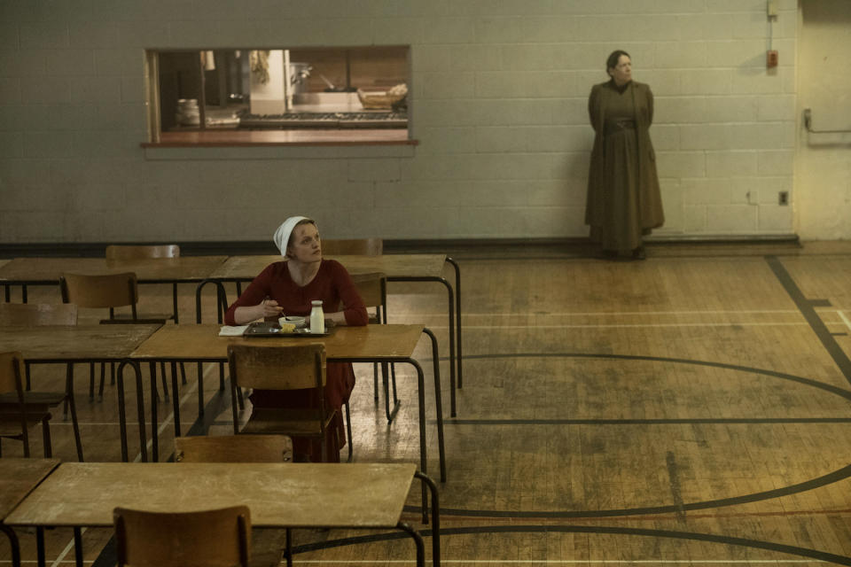 June eats while Aunt Lydia stands in the background