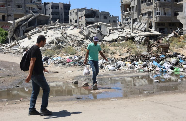Dos palestinos caminan por una calle del barrio de Sheikh Radwan, en el norte de la ciudad de Gaza, junto a edificios destruidos por los bombardeos israelíes, el 3 de julio de 2024 (Omar al Qattaa)