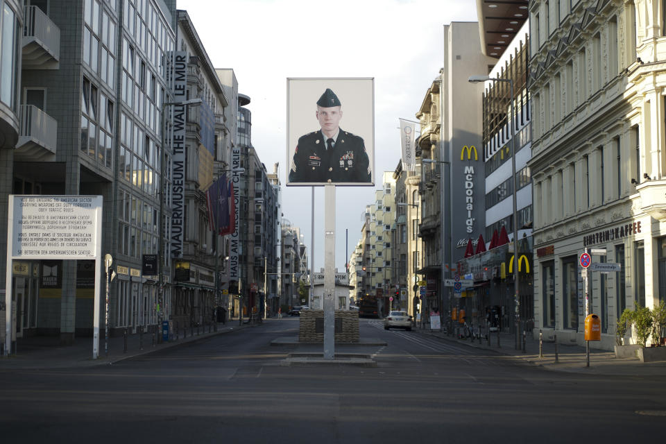 FILE - In this June 9, 2020, file photo, a picture of a former American soldier is displayed at the former U.S. army Checkpoint Charlie in Berlin, Germany. In vowing to pull thousands of U.S. troops from Germany, President Donald Trump is following a pattern of disruptive moves against allies that have dismayed many of his fellow Republicans. Trump has consistently promised to bring American troops home, dismissing the conventional view that a far-flung U.S. military presence, while costly, pays off in the long run by ensuring stability for global trade. Earlier this week he said the 34,500 U.S. troops in Germany would be reduced to 25,000. (AP Photo/Markus Schreiber, File)