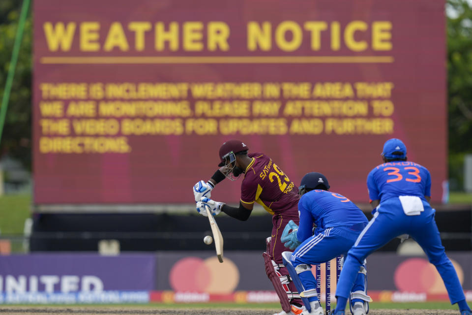 West Indies' Nicholas Pooran plays a shot against India as the board displays a weather notice during the fifth T20 cricket match at Central Broward Regional Park in Lauderhill, Fla, Sunday, Aug. 13, 2023. (AP Photo/Ramon Espinosa)