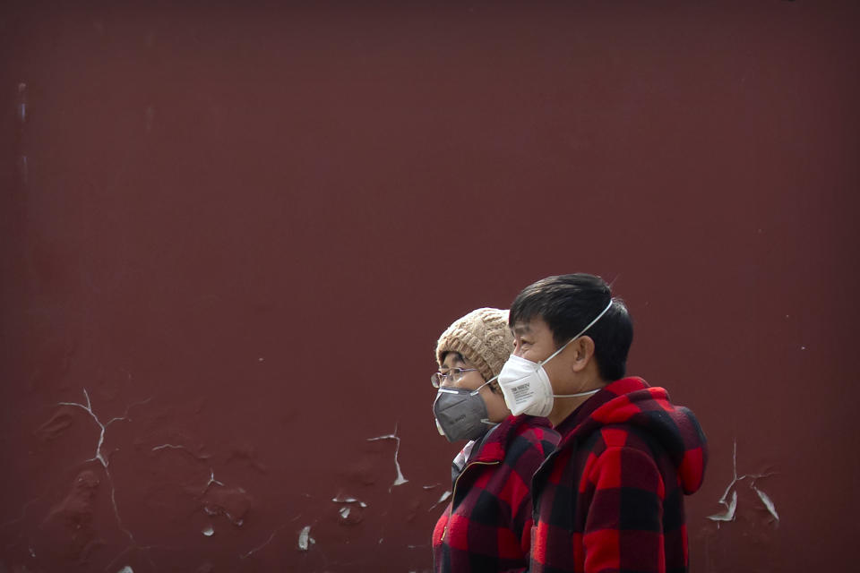 Dos personas con mascarillas sobre la boca pasan por un parque público en Beijing, el 21 de febrero de 2020. (AP Foto/Mark Schiefelbein)