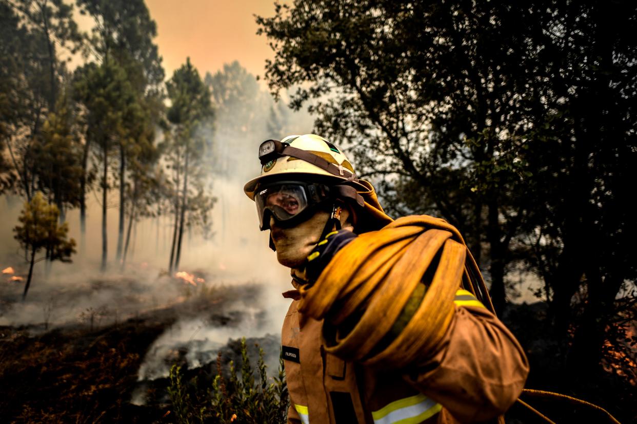 A firefighter carries a hose as a fire squad tries to extinguish a wildfire in the village of Casais de Sao Bento in Macao in central Portugal on July 22, 2019. (Photo: Patricia De Melo Moreira/AFP/Getty Images)