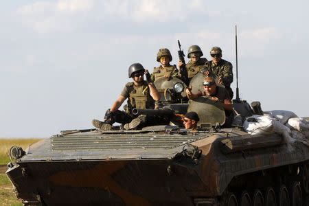 Ukrainian servicemen ride atop an armoured fighting vehicle as they patrol the area in Luhansk region August 21, 2014. REUTERS/Valentyn Ogirenko