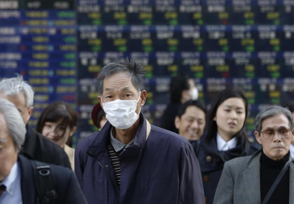 People walk by an electronic stock price indicator in Tokyo Monday, April 7, 2014. Internet and technology stocks tumbled across Asia on Monday as a sell-off spread from Wall Street where investors knocked down such companies over worries about excessively high valuations. (AP Photo/Shizuo Kambayashi)