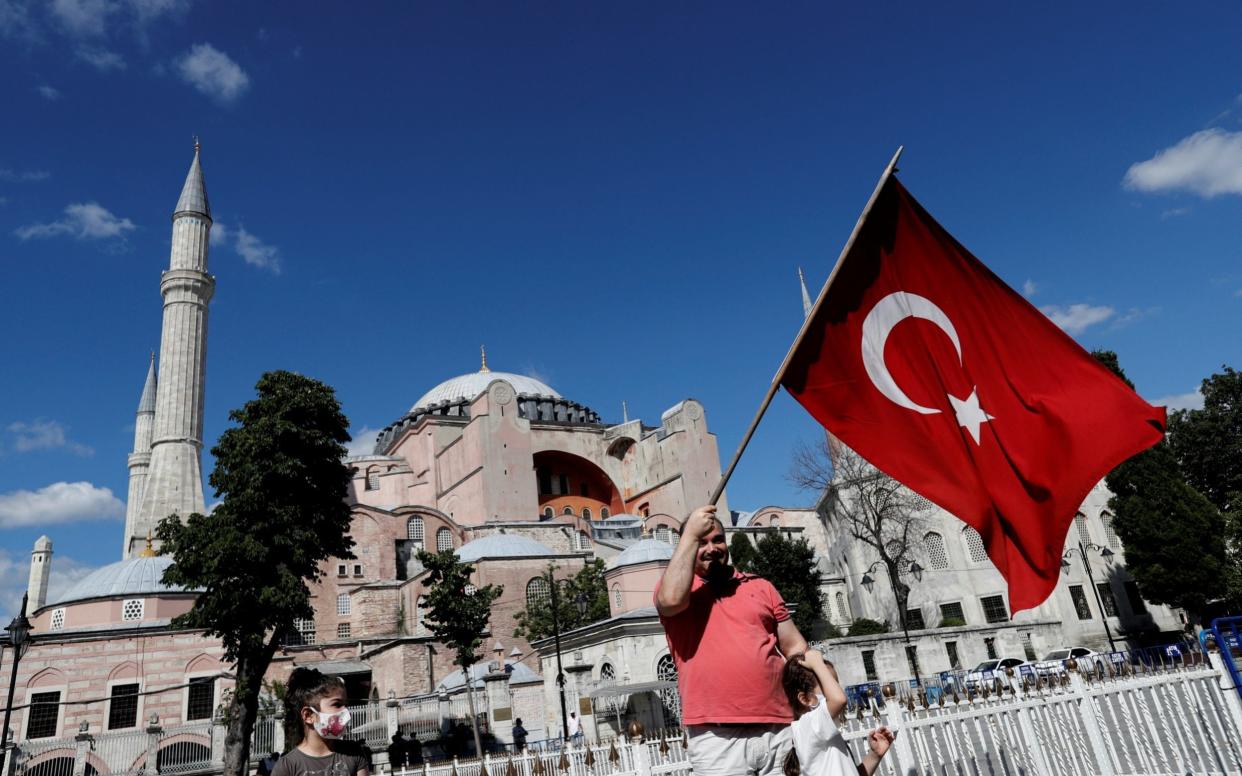 A man waves a Turkish Flag in front of the Hagia Sophia after the court decision - REUTERS/Murad Sezer