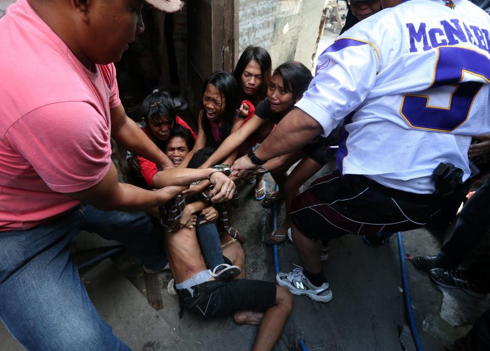 epa04044202 Filipino resident Brix Mercado, 27, (C) is being shielded by his family to prevent the local police from arresting him during a demolition of shanties at Sitio San Roque in Quezon City, east of Manila, Philippines, 27 January 2014. Throwing rocks, pillboxes, and even human waste, illegal settlers barricaded the demolition team in Baranggay Bagong Pag-asa. Four residents were arrested and twelve were reported injured. Residents report receiving cash from 300 to 450 US dollar in exchange for their voluntary relocation. Earlier, hundreds of the urban poor marched to the city hall in protest of the demolition that will pave the way for the rise of a business district. EPA/DENNIS M. SABANGAN