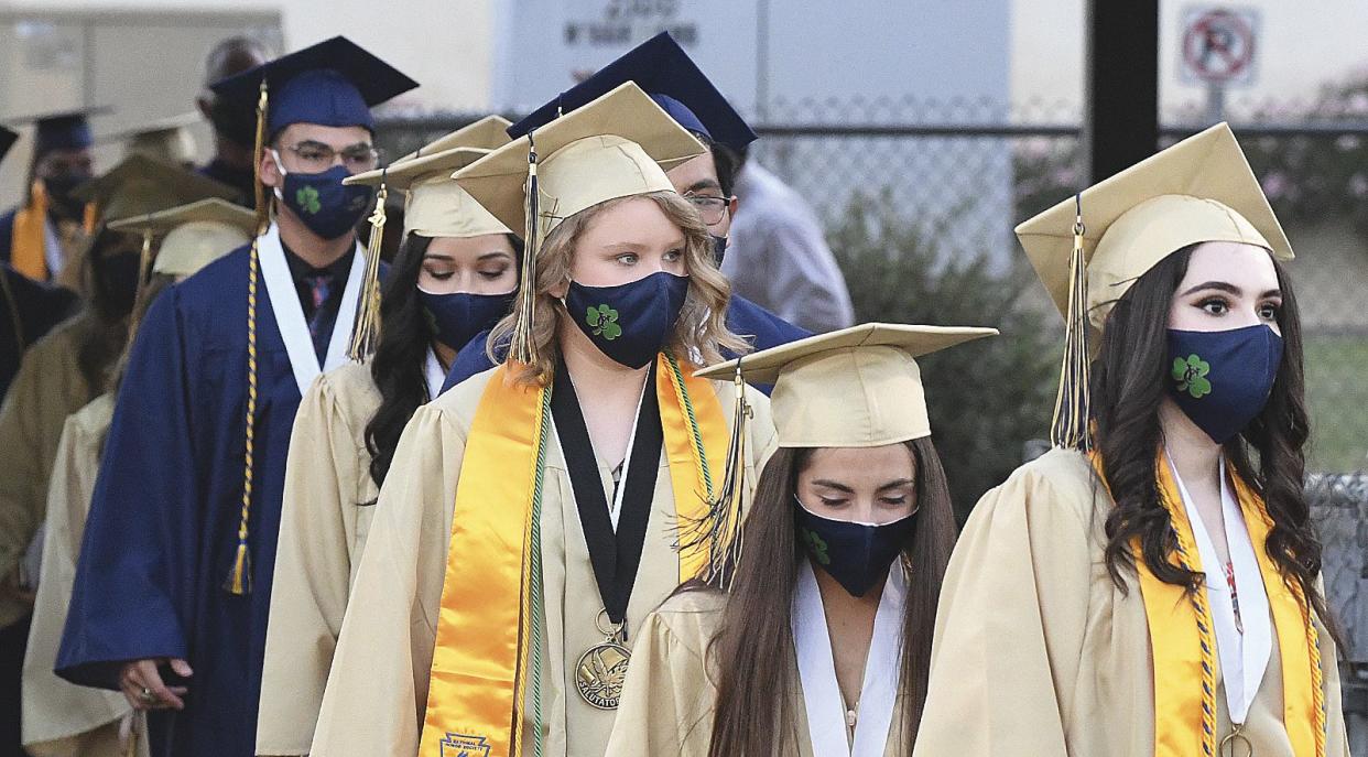 Members of the Class of 2020, all wearing face masks, file into a stadium at Yuma Catholic High School for the graduation ceremony on June 10, 2020 in Yuma, Ariz., during the coronavirus pandemic.