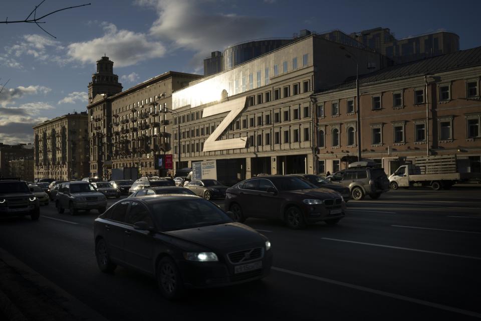 Autos en Moscú, Rusia, circulan el miércoles 30 de marzo de 2022, ante un edificio decorado con una enorme Z, que se ha convertido en símbolo de la operación militar rusa en Ucrania, junto al lema "No abandonamos a los nuestros". Los símbolos son un recordatorio del conflicto que se acerca a cumplir un año. (AP Foto, Archivo)