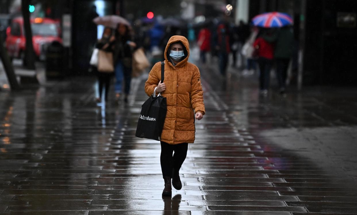 A pedestrian wearing a face mask or covering due to the COVID-19 pandemic, walks in the rain on Oxford Street in London on October 13, 2020, following the announcement of a new three-tiered system categorising areas of England by rates of coronavirus infection. - The British government on Tuesday insisted it is still "guided by science" following criticism that senior ministers had ignored the advice of experts three weeks ago for tougher restrictions to cut rising coronavirus infections. (Photo by DANIEL LEAL-OLIVAS / AFP) (Photo by DANIEL LEAL-OLIVAS/AFP via Getty Images)