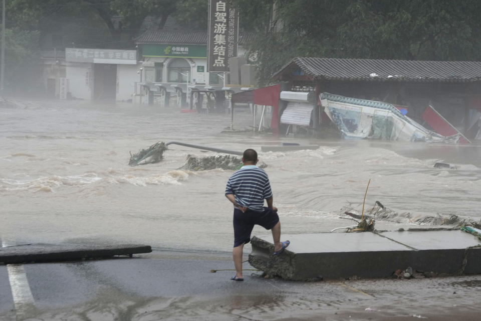 A resident looks out over an area inundated by flood waters in the Miaofengshan region on the outskirts of Beijing, Tuesday, Aug. 1, 2023. Chinese state media report some have died and others are missing amid flooding in the mountains surrounding the capital Beijing. (AP Photo/Ng Han Guan)