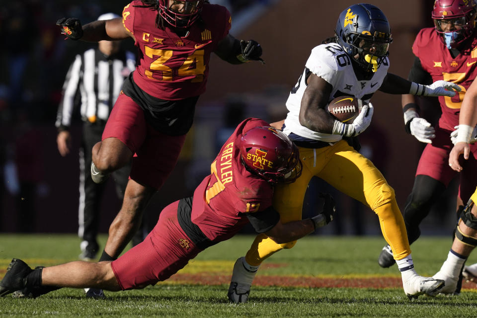 West Virginia running back Justin Johnson Jr. (26) tries to break a tackle by Iowa State defensive back Beau Freyler (17) during the first half of an NCAA college football game, Saturday, Nov. 5, 2022, in Ames, Iowa. (AP Photo/Charlie Neibergall)