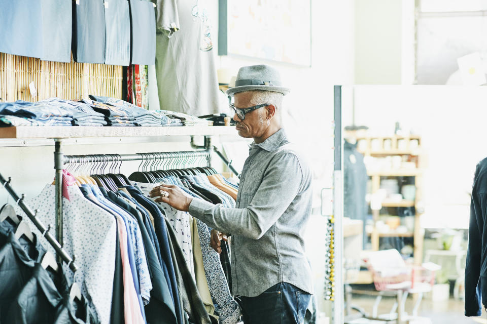 A man inspects suits in a clothing store. The image conveys a professional atmosphere, suggesting relevance to career or money-focused topics