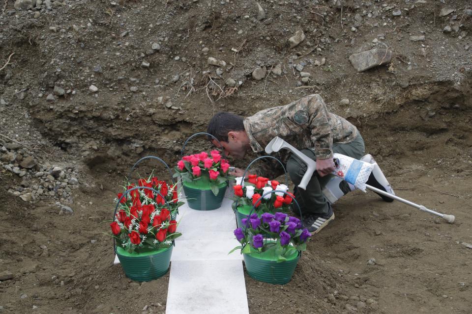 A comrade of Mkhitar Beglarian, an ethnic Armenian soldier of Nagorno-Karabakh army who was killed during a military conflict, pays his last respect during his funeral at a cemetery in Stepanakert, the separatist region of Nagorno-Karabakh, on Sunday, Nov. 15, 2020. Ethnic Armenian forces had controlled Nagorno-Karabakh and sizeable adjacent territories since the 1994 end of a separatist war. Fighting resumed in late September and have now ended with an agreement that calls for Azerbaijan to regain control of the outlying territories as well as allowing it to hold on to parts of Nagorno-Karabakh that it seized during the fighting. (AP Photo/Sergei Grits)