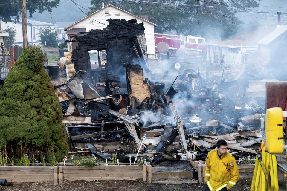 A firefighter passes a home destroyed by the Mill Fire on Saturday, Sept. 3, 2022, in Weed, Calif. (AP Photo/Noah Berger)