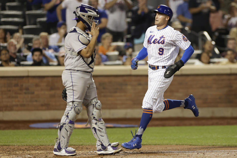 New York Mets' Brandon Nimmo (9) scores a run past Colorado Rockies catcher Elias Diaz during the seventh inning of a baseball game on Saturday, Aug. 27, 2022, in New York. (AP Photo/Adam Hunger)