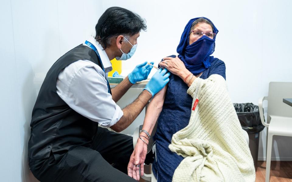 Harbans Kaur, 78, from Smethwick, being vaccinated by an Asda employee - PA