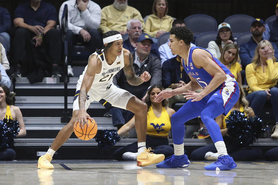 West Virginia guard RaeQuan Battle (21) is defended by Kansas guard Kevin McCullar Jr. (15) during the first half of an NCAA college basketball game on Saturday, Jan. 20, 2024, in Morgantown, W.Va. (AP Photo/Kathleen Batten)