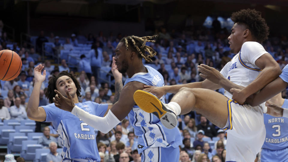 North Carolina guard Elliott Cadeau (2) and forward Jae'Lyn Withers, center, battle UC Riverside guard Niyi Olabode, right, for the ball during the second half of an NCAA college basketball game, Friday, Nov. 17, 2023, in Chapel Hill, N.C. (AP Photo/Chris Seward)