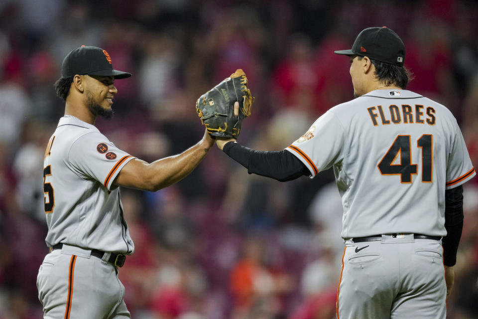 El dominicano Camilo Doval festeja con el venezolano Wilmer Flores, luego que los Gigantes de San Francisco derrotaron a los Rojos de Cincinnati la noche del martes 18 de julio de 2023 (AP Foto/Aaron Doster)