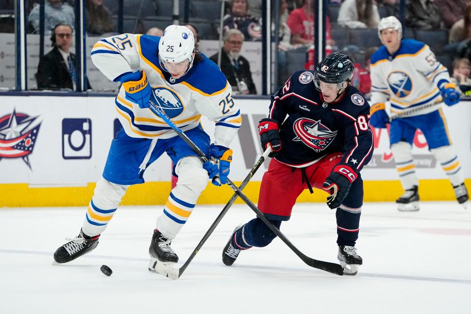 Columbus Blue Jackets left wing Mikael Pyyhtia (82) fights for a puck with Buffalo Sabres defenseman Owen Power (25) during the third period of the NHL hockey game at Nationwide Arena in Columbus on April 14, 2023. The Blue Jackets lost 5-2.