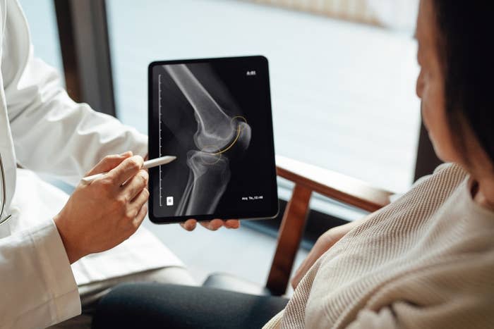 Doctor showing a knee X-ray to a patient, indicating details with a pen