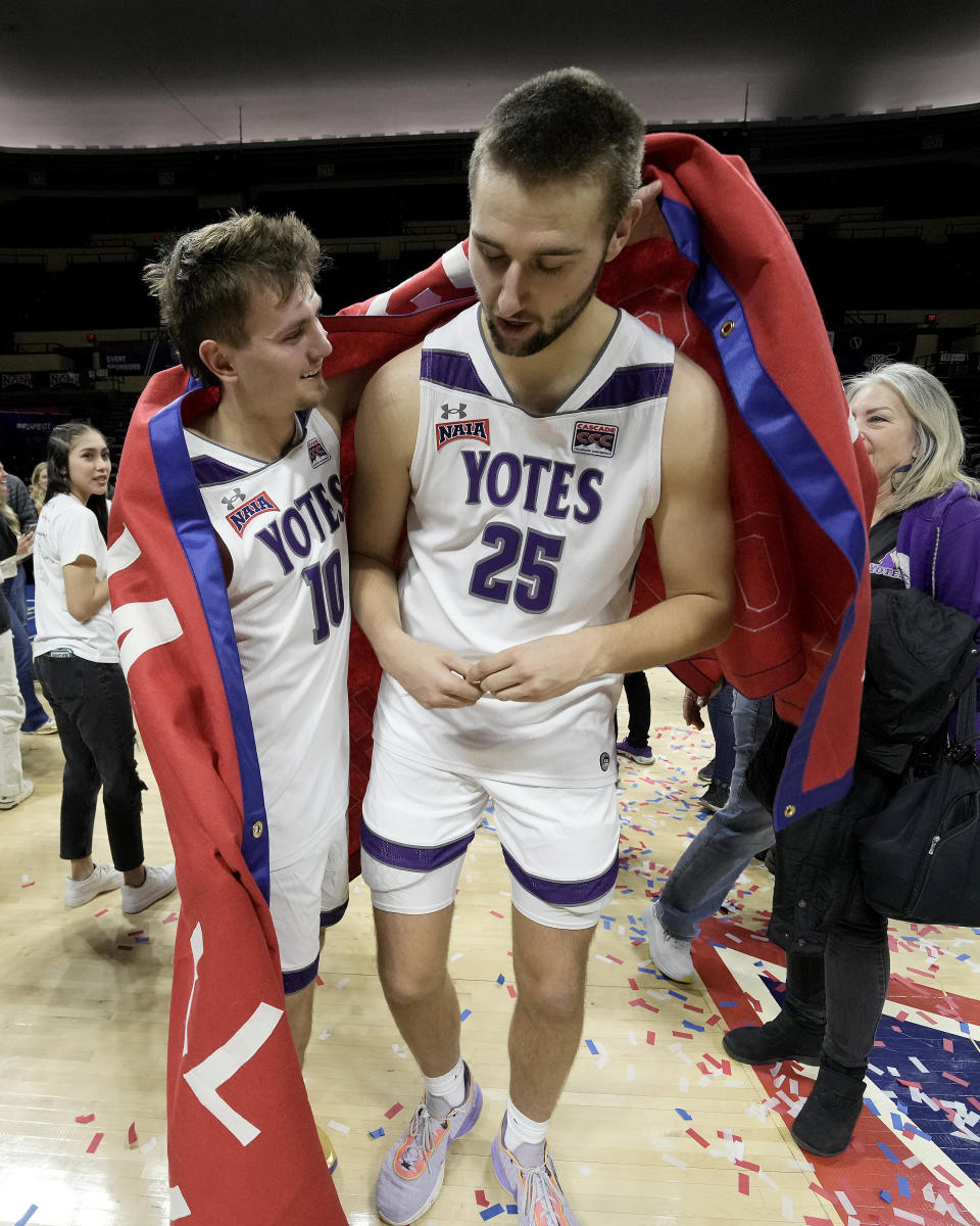 College of Idaho guard Conner Cooper (10) and center Paul Wilson (25) celebrate after their NAIA men's national championship college basketball game against Indiana Tech Saturday, March 18, 2023, in Kansas City, Mo. College of Idaho won 73-71. (AP Photo/Charlie Riedel)