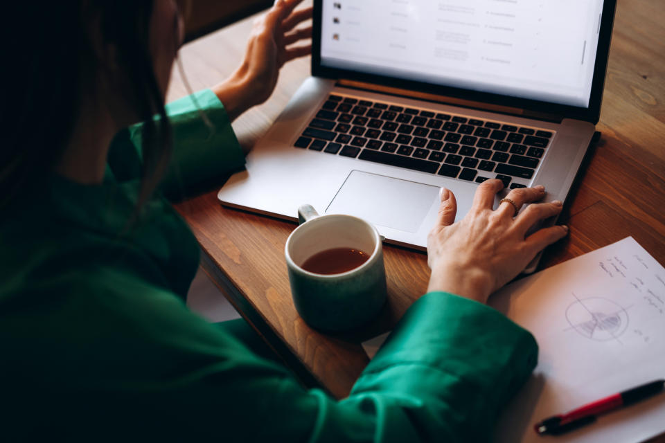 A woman's hands on a laptop that sits on a desk