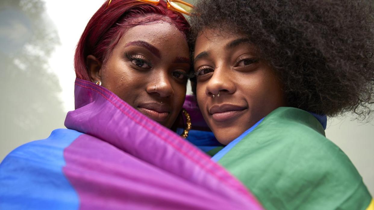 two women wrapped in pride flag