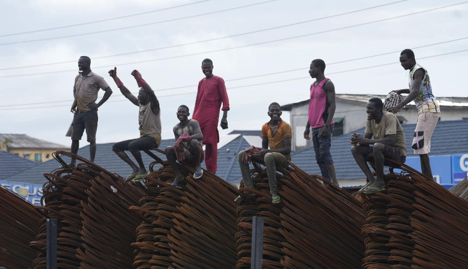 Workers cheers as supporters of Nigeria Labour Party's Presidential Candidate Peter Obi march past their worksite during a rally in Lagos, Nigeria, Saturday Oct. 1, 2022. Presidential candidates in Nigeria's forthcoming election signed on Thursday, Sept. 29, 2022. an accord committing to a peaceful campaign for the West African nation's 2023 presidential election.(AP Photo/Sunday Alamba)