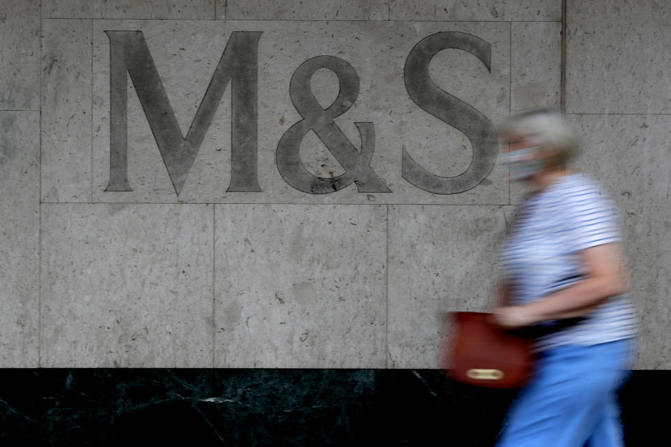 A woman passes the sign on a branch of Marks and Spencer in London, Tuesday, Aug. 18, 2020. Marks and Spencer has said it will cut 7,000 jobs over the next three months as the UK retailer overhauls its business in the latest sign of how the coronavirus pandemic has disrupted the high street. (AP Photo/Kirsty Wigglesworth)