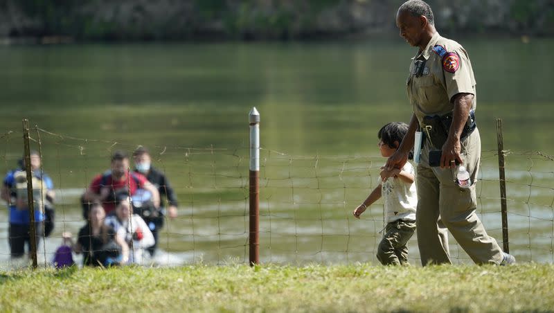 A Texas Department of Public Safety officer walks with a young boy after a group of migrants who crossed the border turned themselves in on June 16, 2021, in Del Rio, Texas.