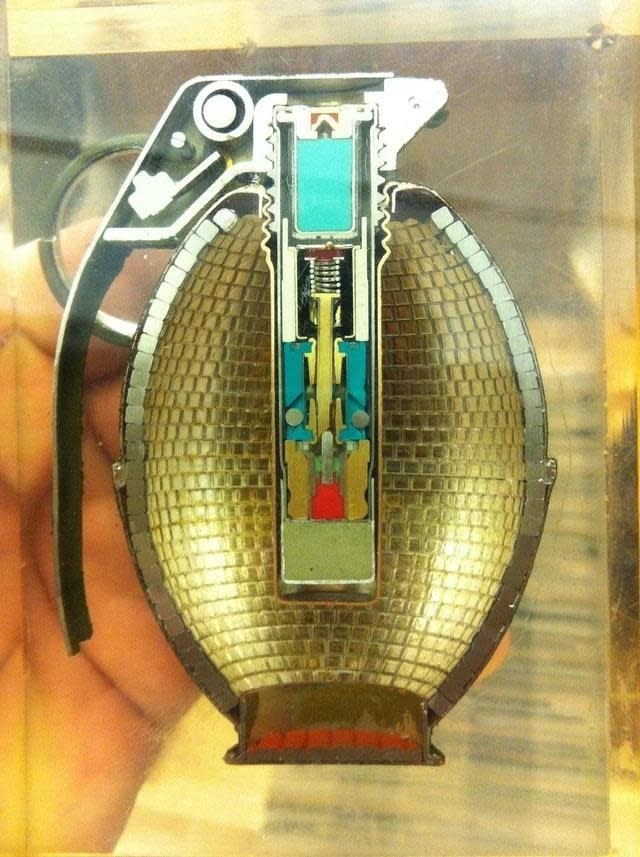 Half a grenade has been removed to reveal what it looks like inside, which features a spring, pin, and a powder at the bottom