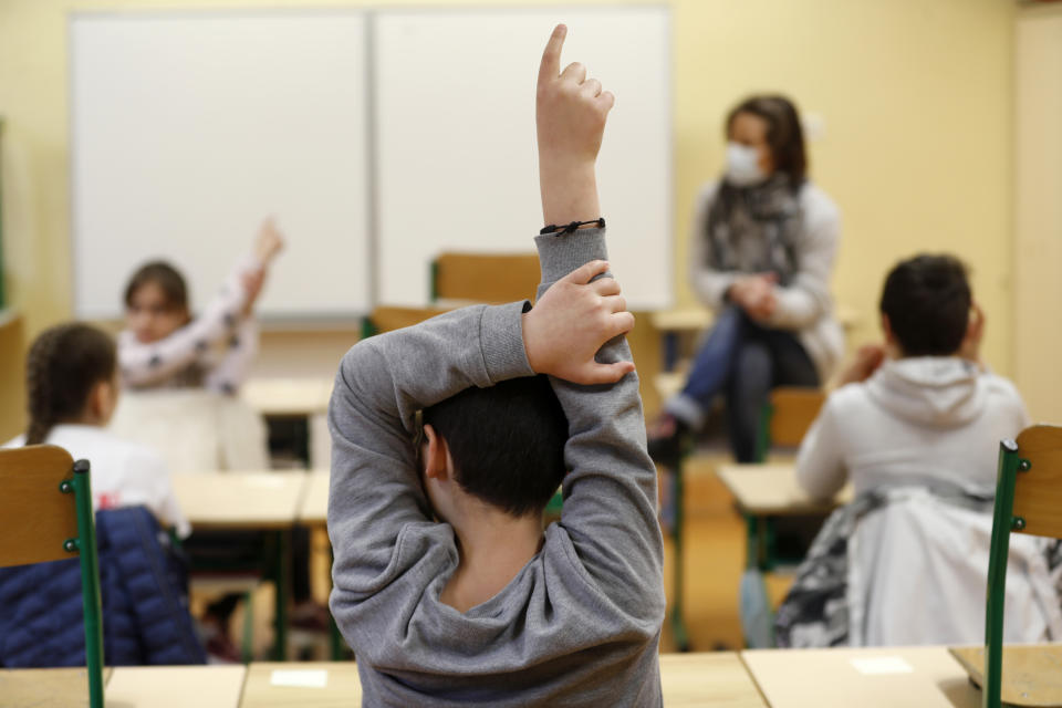 FILE - In this May 14, 2020 file photo, schoolchildren raise their fingers to answer their teacher Sandrine Albiez, wearing a face masks, in a school in Strasbourg, eastern France. Just days after around a third of French schoolchildren went back to school, ended the gruelling coronavirus-linked lockdown, there has been flare up of about 70 cases with coronavirus in classes. (AP Photo/Jean-Francois Badias, File)