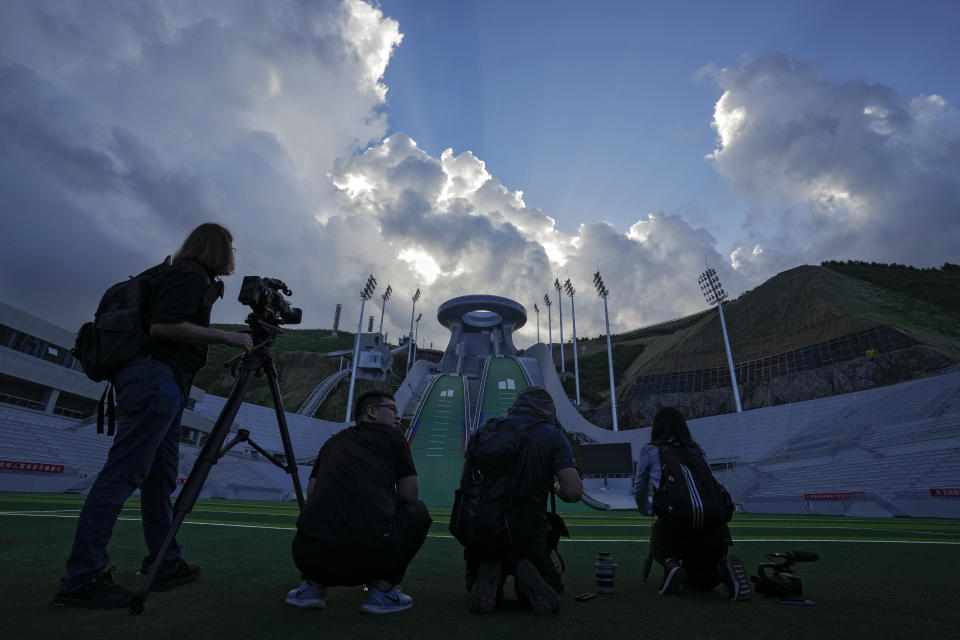 FILE - In this July 14, 2021, file photo, journalists film the National Ski Jumping Centre, one of the venues for Beijing 2022 Olympic and Paralympic Winter Games, during a media tour in Zhangjiakou in northwestern China's Hebei province. The IOC says the Olympics are only about the sports; no politics allowed. But reporters from other countries who puncture the PR skin to explore other aspects of life in China — as they have in Japan during the Tokyo Olympics — could draw more than criticism. (AP Photo/Andy Wong, File)