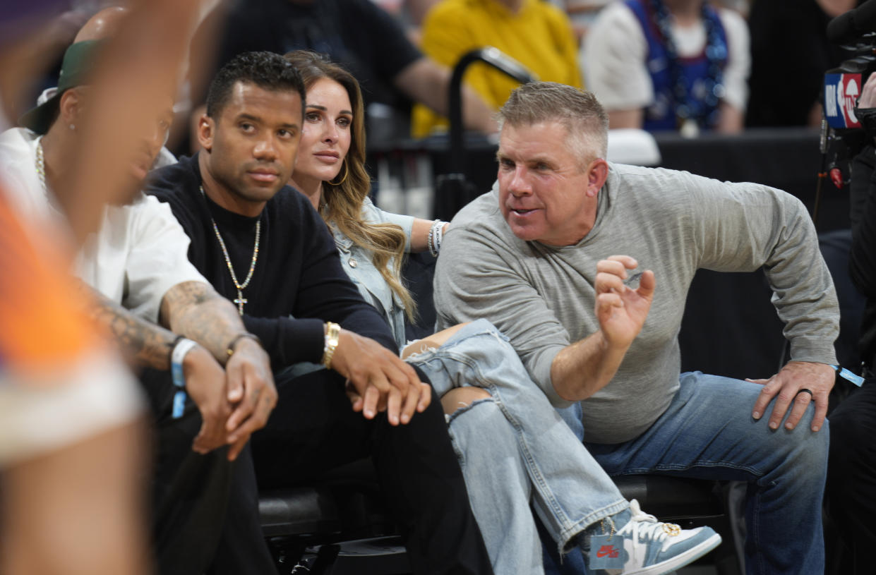 Denver Broncos head coach Sean Payton, right, chats with quarterback Russell Wilson, left, as Payton's wife, Skylene, looks on from courtside seats during a Denver Nuggets playoff game. (AP Photo/David Zalubowski)