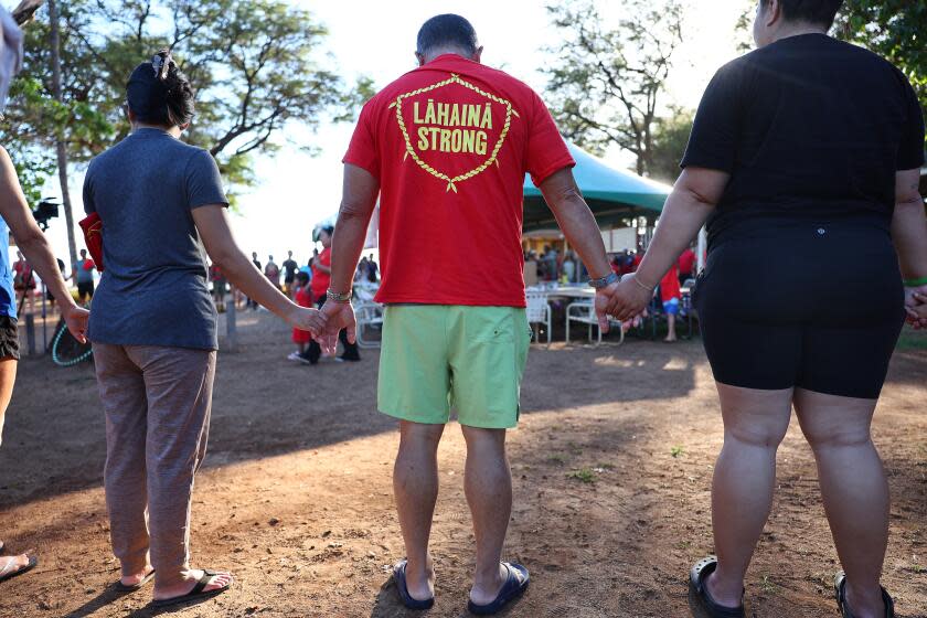 LAHAINA, HAWAII - OCTOBER 06: Community members hold hands in a prayer circle at a 'Lahaina Strong' gathering on October 6, 2023 in Lahaina, Hawaii. Community members painted signs expressing their opposition to the October 8th start of tourists returning to west Maui following the devastating wildfire. The wind-whipped wildfire on August 8th killed at least 98 people while displacing thousands more and destroying over 2,000 buildings in the historic town, most of which were homes. A phased reopening of tourist resort areas in west Maui is set to begin October 8th on the two-month anniversary of the deadliest wildfire in modern U.S. history. Many local residents feel that the community needs more time to grieve and heal before reopening to tourism. (Photo by Mario Tama/Getty Images)