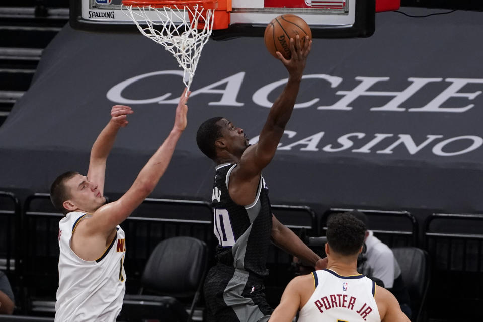 Sacramento Kings forward Harrison Barnes, center, goes to the basket between Denver Nuggets' Nikola Jokic, left, and Michael Porter Jr., right, during the first half an NBA basketball game in Sacramento, Calif., Saturday, Feb. 6, 2021. (AP Photo/Rich Pedroncelli)
