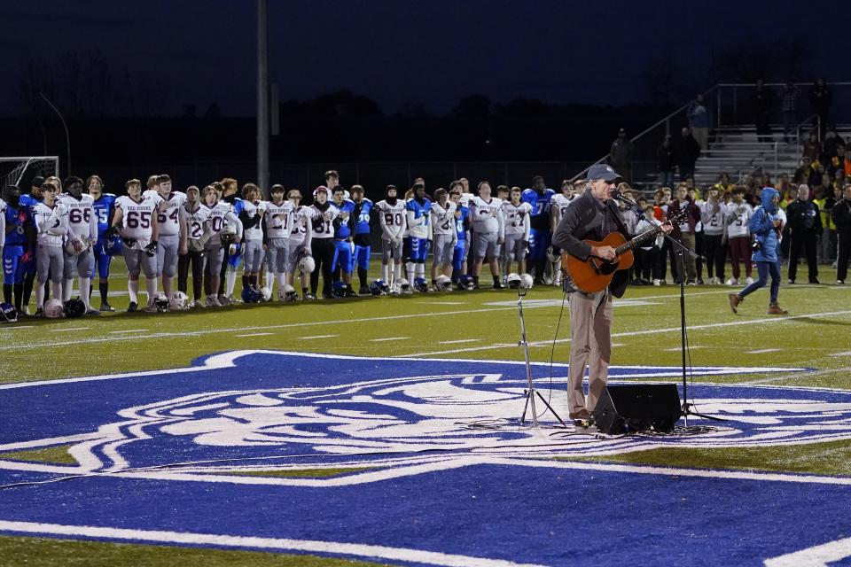 Singer James Taylor sings the national anthem as Lewiston High School and Edward Little High School players stand together, Wednesday, Nov. 1, 2023, prior to a high school football game in Lewiston, Maine. Locals seek a return to normalcy after a mass shooting on Oct. 25. (AP Photo/Matt York)