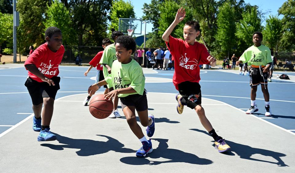 A group of youngsters play basketball during the "Play 4 Peace" 3-on-3 basketball tournament at Harambee Park in Boston, July 30. The second annual event was created by a group of friends from the Lincoln-Sudbury Class of 1988.