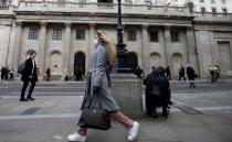 A woman, wearing a protective face mask, walks in front of the Bank of England, following an outbreak of the coronavirus, in London
