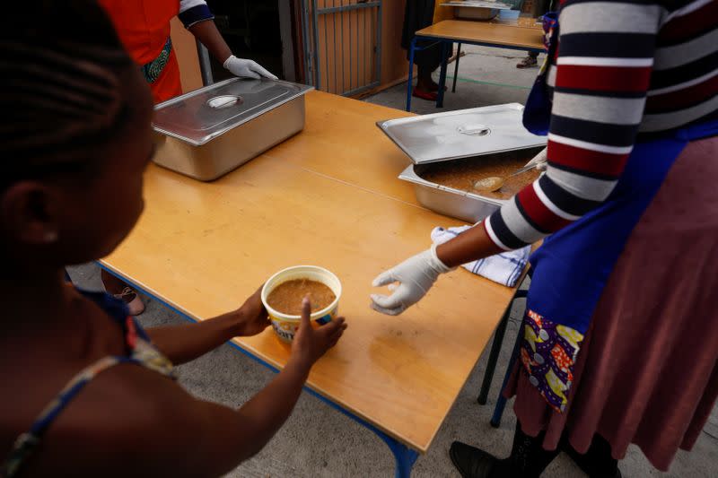 Volunteers and teachers serve food at a school feeding scheme in Gugulethu township during a nationwide lockdown aimed at limiting the spread of coronavirus disease (COVID-19) in Cape Town