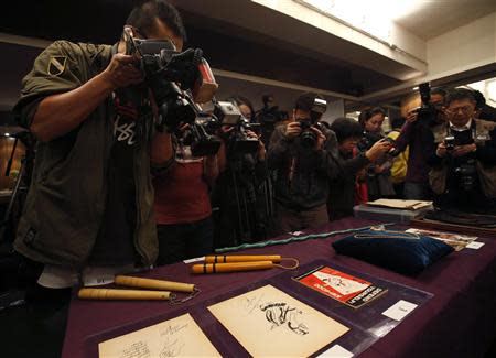 Journalists take photos and videos of items used or created by the late kungfu superstar Bruce Lee, including nunchakus and drawings, as part of the Bruce Lee 40th anniversary collection, at a news conference in Hong Kong December 2, 2013. REUTERS/Bobby Yip