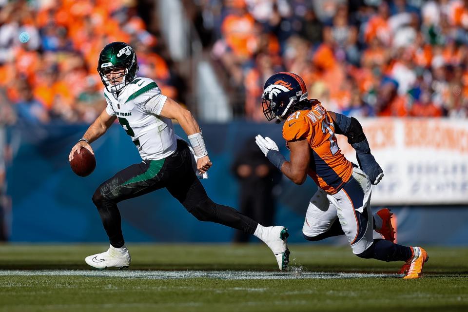 New York Jets quarterback Zach Wilson (2) scrambles under pressure from Denver Broncos cornerback K'Waun Williams (21) in the second quarter at Empower Field at Mile High.