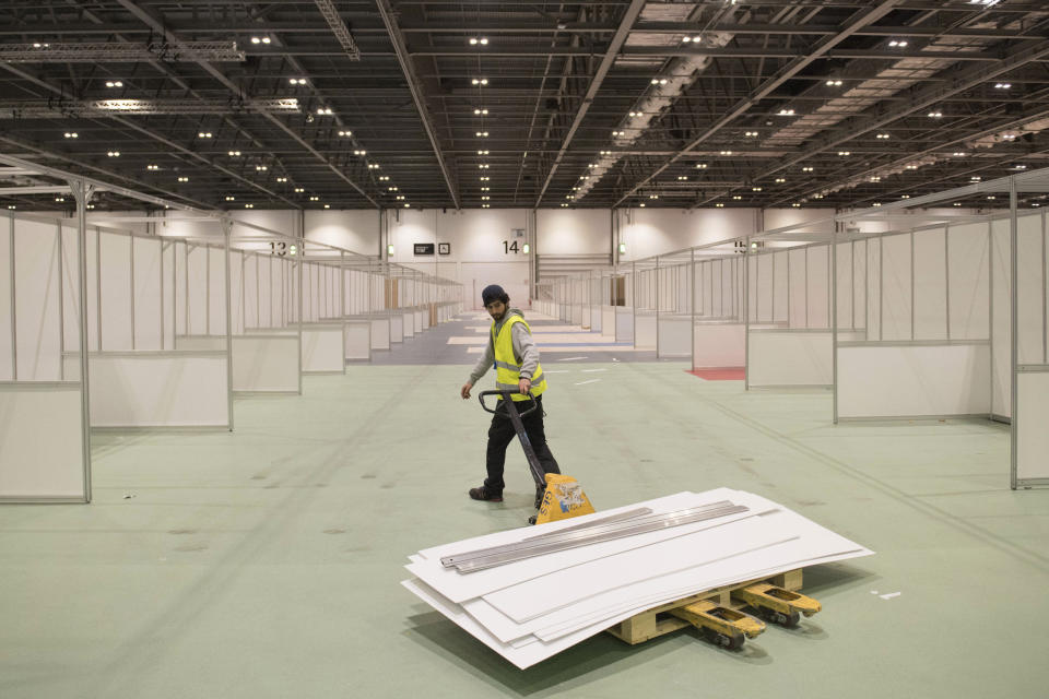 FILE - In this Tuesday, March 31, 2020 photo work continues at the ExCel centre which is being made into a temporary hospital called NHS Nightingale in London. Britain's National Health Service, cornerstone of the nation's post-war welfare state, may be stretched to the breaking point in coming weeks as hospitals brace for an expected tsunami of critically ill patients when the coronavirus pandemic reaches its peak across the United Kingdom. (Stefan Rousseau/Pool Photo via AP, File)